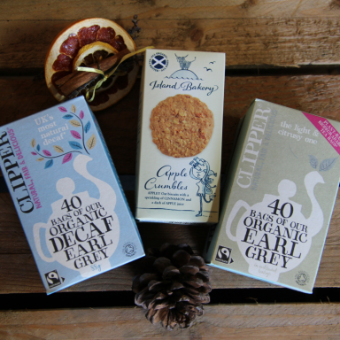 Three boxes of organic tea, with a pine cone and wooden background.