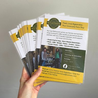 A hand holding several leaflets promoting a community farm shop.