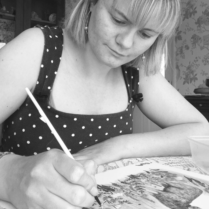 Chantelle with short hair painting a picture at a table.