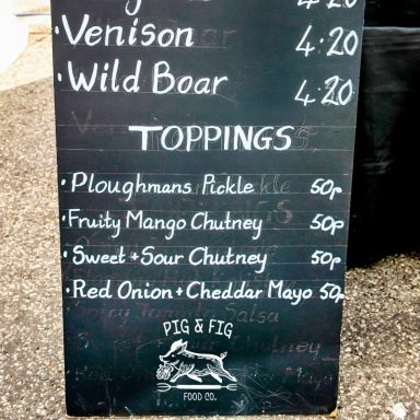 Menu board featuring venison, wild boar, and various toppings with prices.