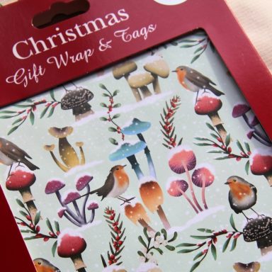 Christmas gift wrap featuring birds, mushrooms, and foliage on a light green background.