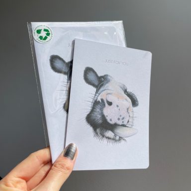 A person holding two eco-friendly cards featuring a cow illustration.