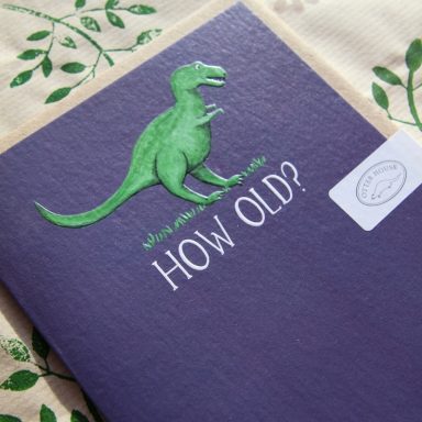A purple card featuring a green dinosaur and the text "HOW OLD?"