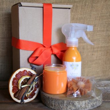 Gift box containing orange-scented products: spray, candle, and dried orange slice.