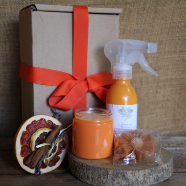 Gift box with orange-themed products, including a spray bottle and a candle.