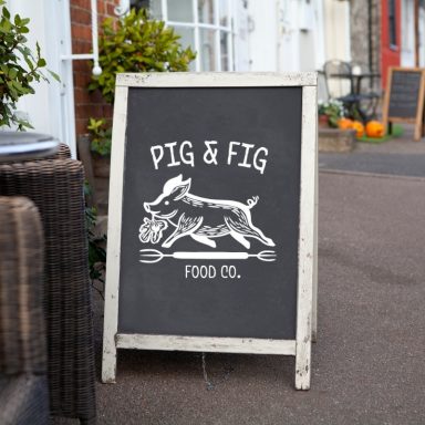 A chalkboard sign displaying "Pig & Fig Food Co." with a running pig illustration.